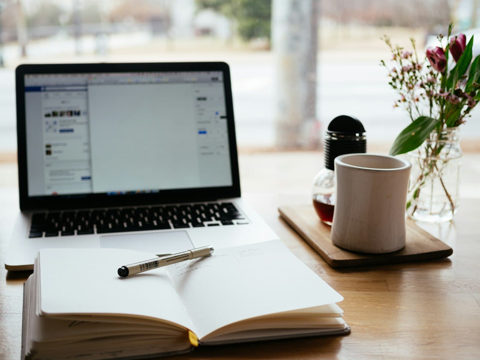 An open book beside a laptop on a study desk